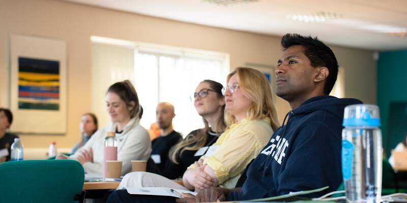 Four students watching lecture happening out of frame